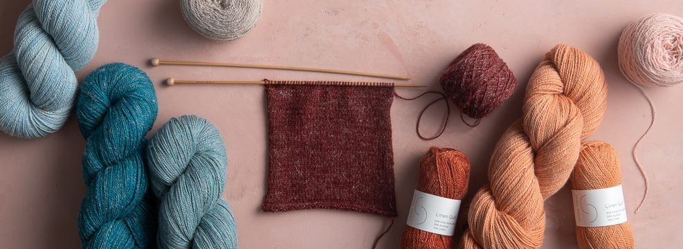In-progress swatch of Linen Quill in Red Chestnut, plus skeins and Linen Quill Minis in various colors.